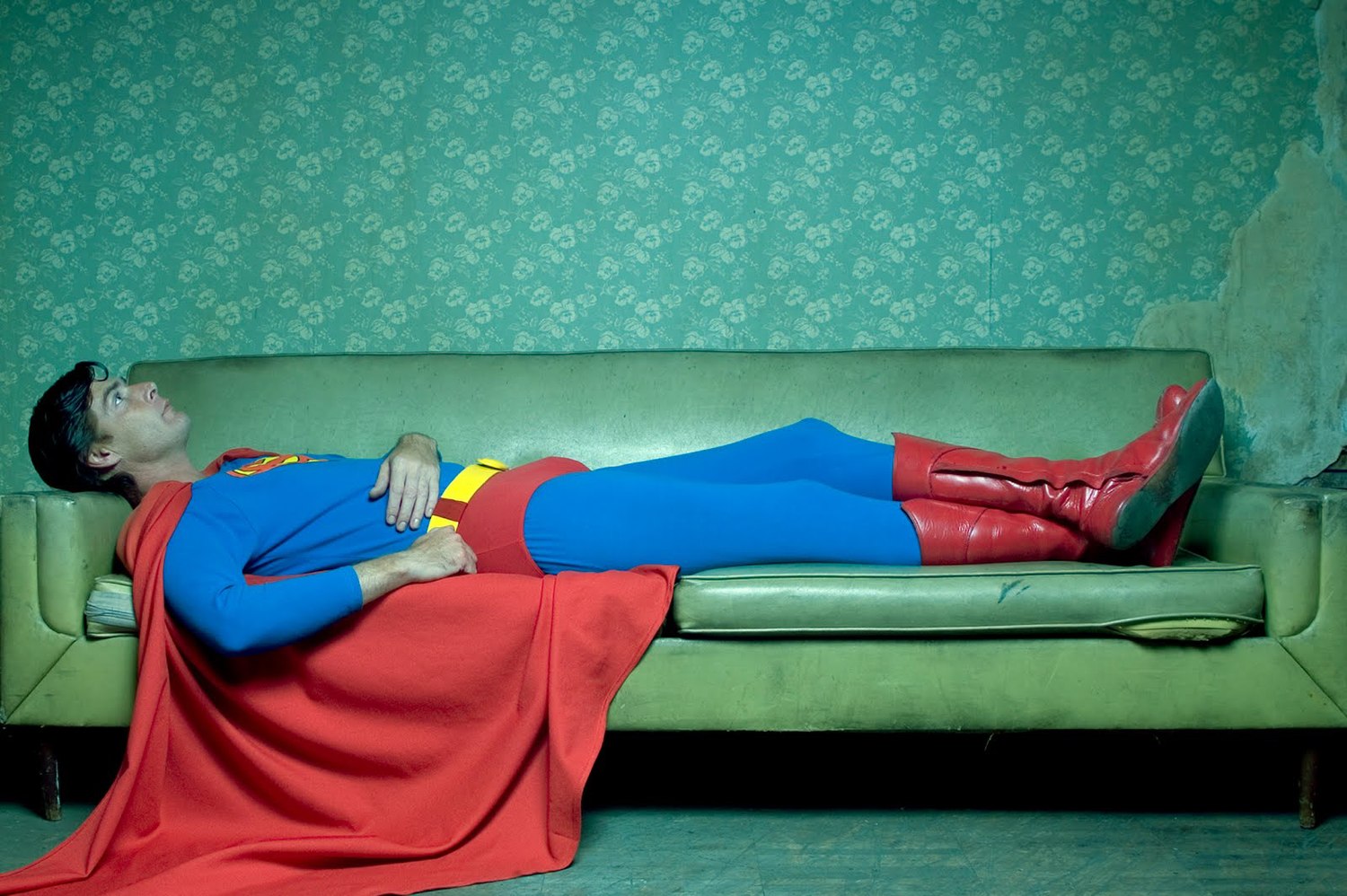 Superman laying down on a green couch