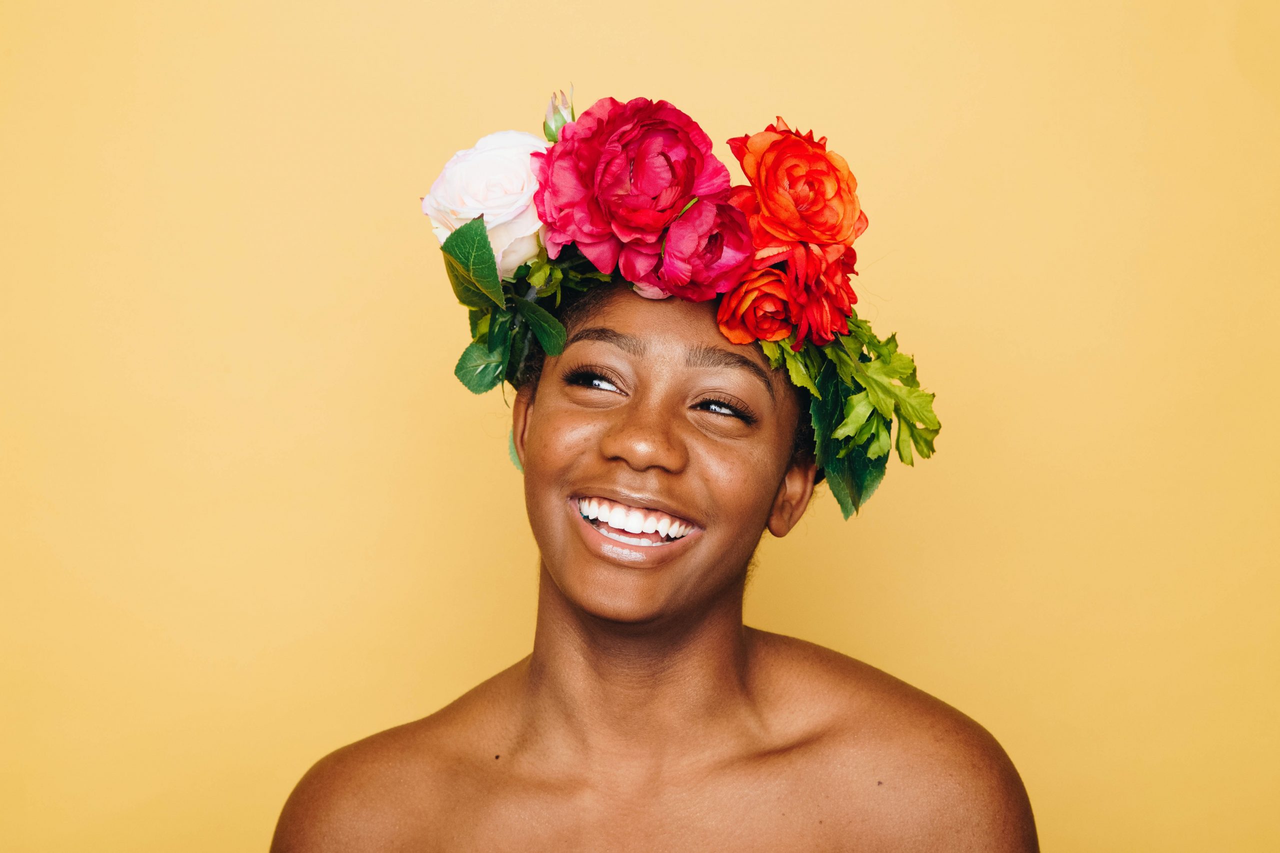 Confidence, a young woman with a headband made of flowers smiles and looks happy