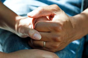 Two Adults holding hands supportively