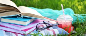 Sunglasses, books and a cold drink resting on the grass